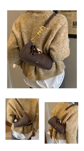 Détail du sac croissant marron foncé avec boucles dorées CH et pendentif rétro