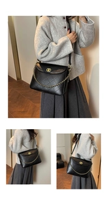 Detail of black quilted tote bag with gold chain strap and metal turn-lock closure