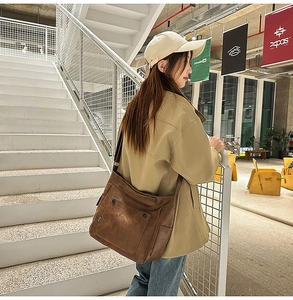 Detail of a large capacity brown matte leather tote bag featuring functional front pockets