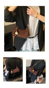 Vue détaillée du sac hobo en daim marron foncé avec pompon et breloque sur le mannequin