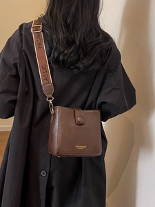 Deep brown leather bucket bag with wide jacquard shoulder strap and vintage style