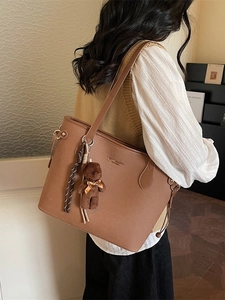 Vintage brown leather tote bag with teddy charm and striped rope on a female model