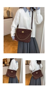 Close-up of brown suede quilted messenger bag with gold hardware and chain detail