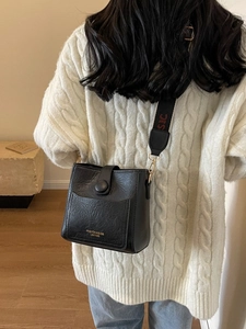 Retro black bucket bag with wide shoulder strap shown on model in cozy sweater