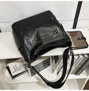 Detailed macro view of the black PU leather texture and silver buckle on the tote bag