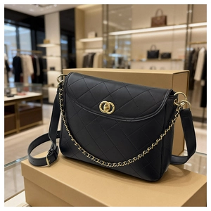 Detail of black quilted leather bag with gold chain strap and classic buckle on boxes