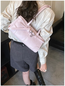Détail du sac bandoulière rose rectangulaire avec lanières croisées et boucles métalliques