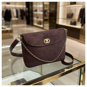Detail of dark brown quilted suede shoulder bag with gold interlocking buckle and chain