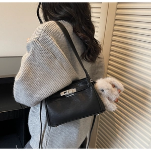 Detail of black pebbled leather handbag with silver rotary lock and white bunny charm
