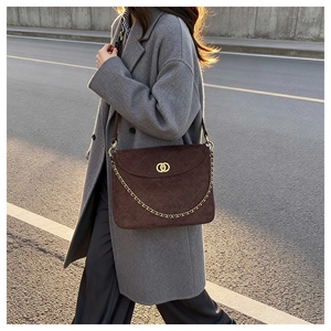 Brown suede messenger bag with quilted pattern and gold chain shown in a street style view