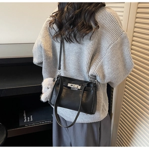 Detail of vintage black leather Kelly bag with silver clasp and plush bunny keychain