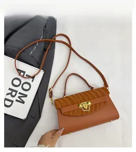 Detail of brown leather bag with wave texture, golden metal buckle and chain accent