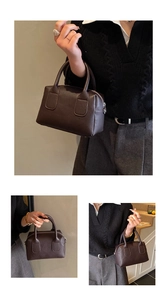 Detail of dark brown baguette bag showing pebbled leather texture and elegant top handle