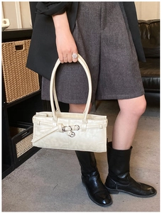 Gros plan d'un sac à main beige rectangulaire avec boucles et finitions minimalistes