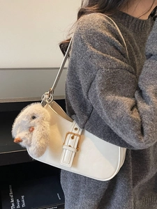 White glossy crescent shoulder bag with plush rabbit charm and gold metal buckle detail