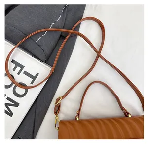 Detail of brown wavy embossed leather handbag with adjustable gold-tone shoulder strap