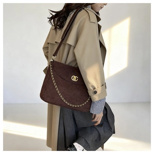 Detail of dark brown suede messenger bag with gold chain and quilted diamond pattern