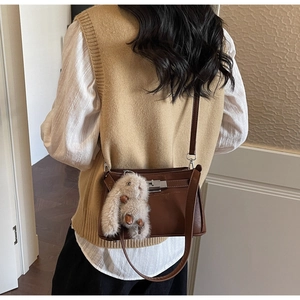 Close-up of vintage brown leather bag with metal buckle and plush bunny charm accessory