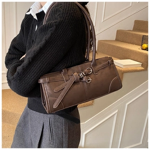 Sac baguette marron foncé avec boucle métallique porté par un mannequin en intérieur