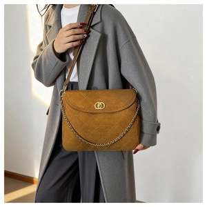 Detail of camel suede messenger bag with diamond stitching and golden circular clasp