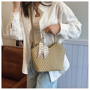 Détail du sac à main matelassé vert olive avec un foulard pied-de-poule sur l'anse