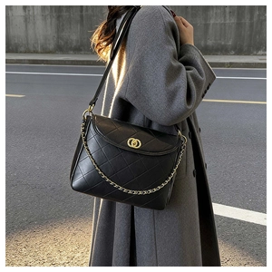 Detailed view of black quilted leather crossbody bag with gold interlaced hardware