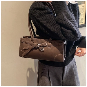 Détail d'un sac à bandoulière en cuir mat marron foncé avec boucles sur modèle
