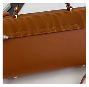 Close-up of brown handbag featuring wavy embossed texture and gold metal hardware
