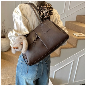 Detailed side view of large brown faux leather tote bag with cute plush bunny pendant
