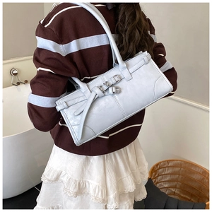 Détail d'un sac porté épaule bleu clair avec boucles argentées dans un décor intérieur