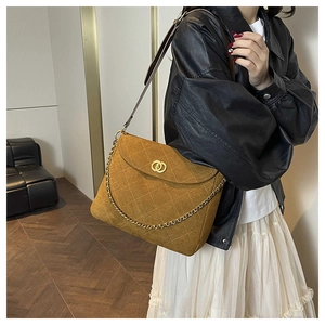 Detail of a brown quilted suede messenger bag with gold chain and double ring lock
