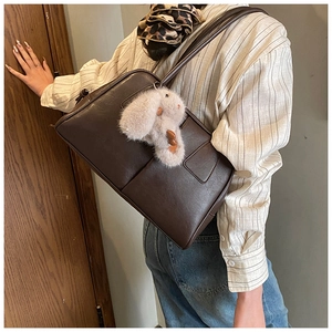 Detail of dark brown Boston bag featuring premium faux leather texture and plush bunny charm