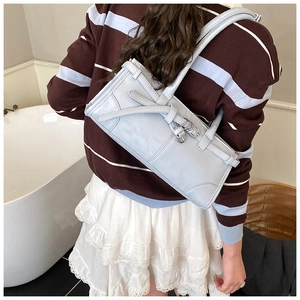 Détail d'un sac à bandoulière bleu clair avec nœud porté par un mannequin femme