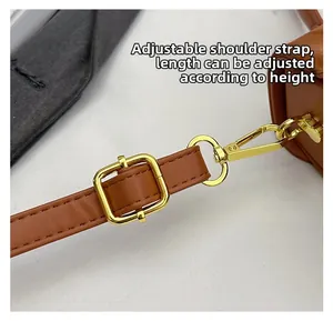 Detail of adjustable brown leather shoulder strap with gold buckle and metal carabiner