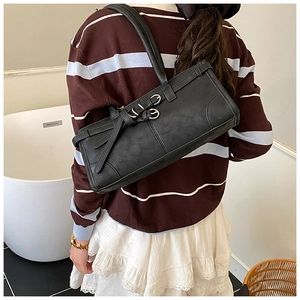 Gros plan d'un sac sous les bras en cuir noir mat avec des boucles vintage sur la bandoulière