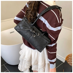Détail du sac sous le bras en cuir noir avec anneaux argentés et sangle sur le modèle