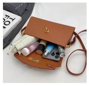 Detail view of large capacity brown leather crossbody bag with golden twist lock closure
