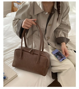 Detail of soft dark brown leather Boston bag with dual zippers in a lifestyle setting