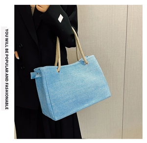 Detail of light blue denim tote bag with woven rope handles and metallic eyelets