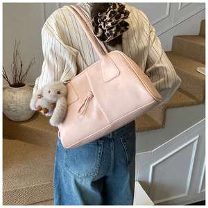 Rear view of a light pink Boston bag with a cute plush rabbit charm on a shoulder strap