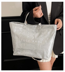 Chic silver tote bag with snake skin texture held by model for a modern fashion look
