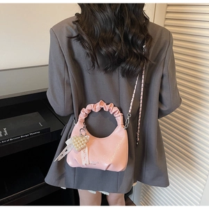 Pink patent leather handbag with pleated handle and heart pearl charm detail view
