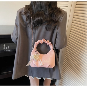 Detail of light pink pleated moon bag with pearl heart charm and satin ribbon accent