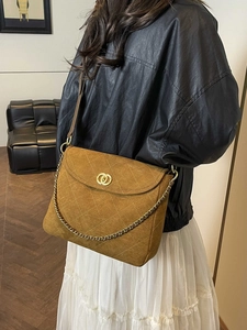Brown suede quilted shoulder bag with gold chain and metal lock on a fashion model