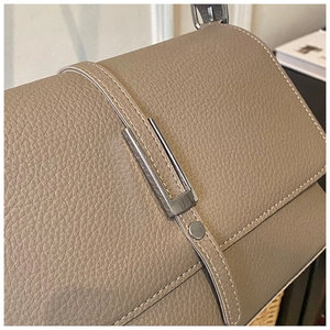 Detailed macro view of gray lychee leather texture and silver buckle on shoulder bag