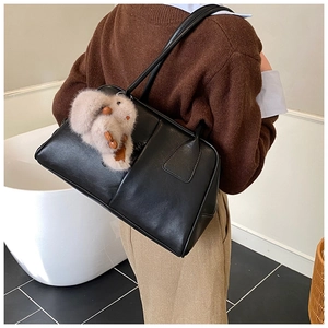 Detail of black faux leather Boston bag featuring a plush rabbit pendant and twin straps