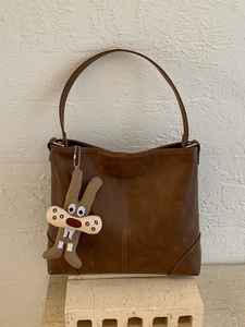 Large soft leather tote bag in dark brown with decorative bunny charm on porous base