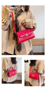 Detailed view of red crossbody bag with golden chain buckle and textured finish