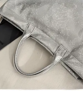 Close-up of silver snakeskin pattern tote bag featuring reinforced handles and metal finish