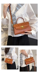 Detail of brown handbag showing golden metal lock and elegant pleated texture on the flap